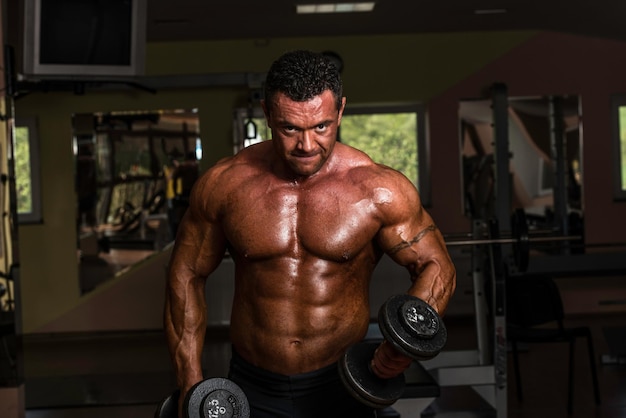 bodybuilder doing heavy weight exercise for biceps with dumbbell