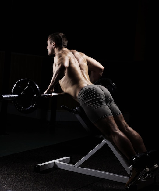 Bodybuilder is engaged in a simulator in the gym