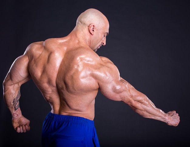 Photo bodybuilder is posing, showing his muscles.