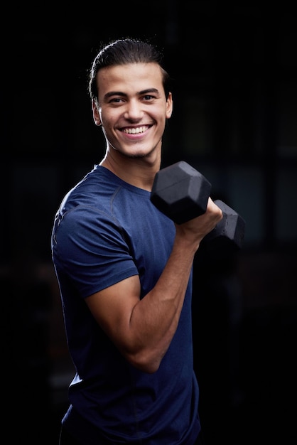 Bodybuilder man studio portret en gewichtheffen met glimlach voor fitness spierontwikkeling en gezondheid Gelukkig bodybuilding atleet halter en zwarte achtergrond voor training, training en zelfzorg