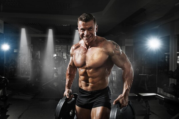 Photo bodybuilder muscle athlete training with weight in gym