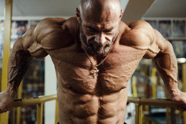 Bodybuilder oppompen van borstspieren push-ups bars