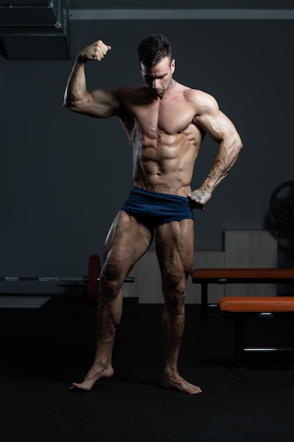 Bodybuilder Performing Front Biceps Pose In Gym