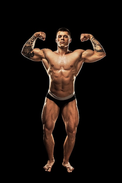 Bodybuilder poseren. Mooie sportieve kerel mannelijke macht. Fitness gespierd lichaam. Geïsoleerd op zwarte achtergrond