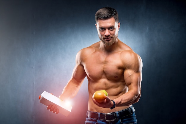 Bodybuilder sportsman holding fruits and juice