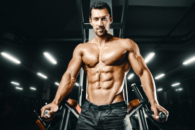 Bodybuilder strong man pumping up abs muscles