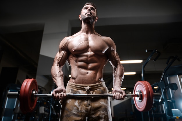 Bodybuilder strong man pumping up biceps muscles