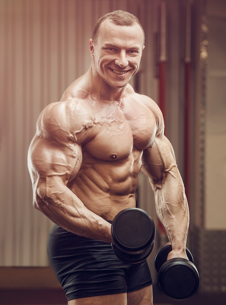 Bodybuilder strong man pumping up biceps muscles