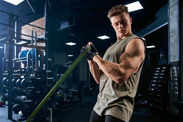Photo bodybuilder training biceps with resistance band.
