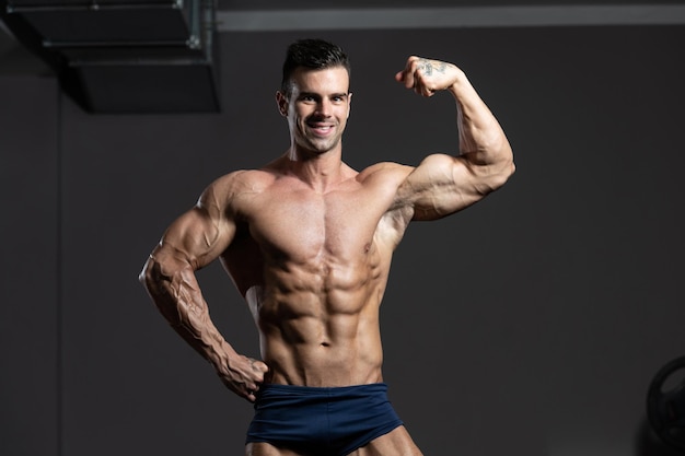 Bodybuilder uitvoeren van front biceps pose in sportschool