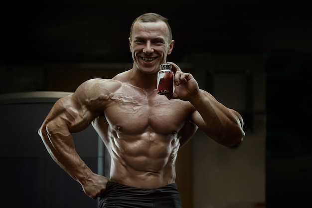 Bodybuilder with protein powder supplements jar