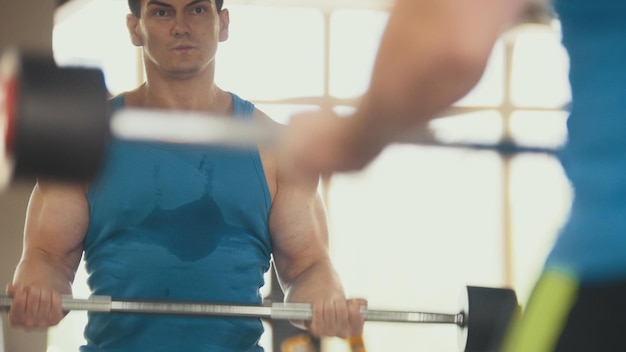 写真 ジムでのボディービル-鏡の近くで上腕二頭筋をトレーニングしている筋肉質の男
