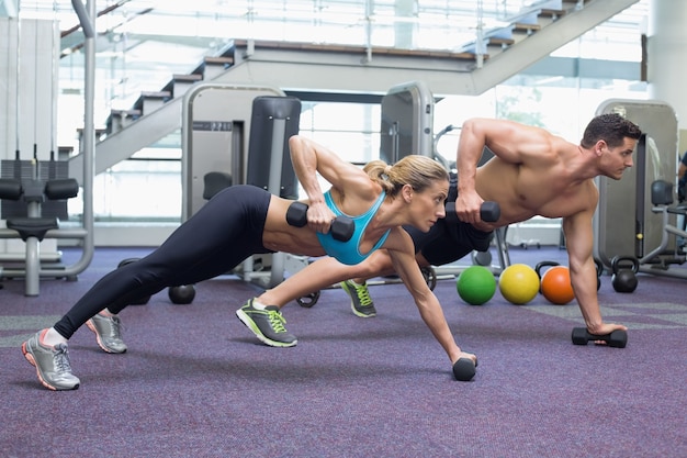 Bodybuilding man en vrouw met halters in plank positie