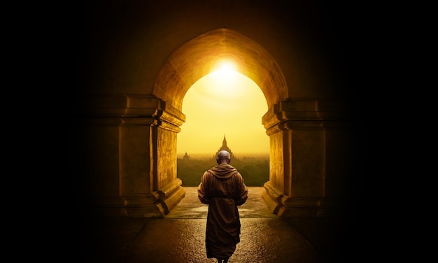 Boeddhistische monnik loopt de tempel binnen terwijl de zon erop schijnt