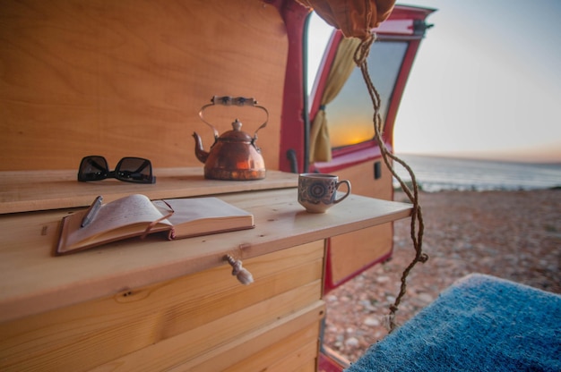 Foto boek en beker in een camper op het strand.