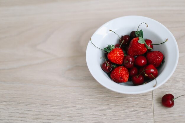 boek en verse zoete kersen en aardbeien op houten achtergrond