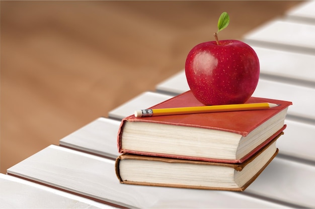 Boeken, appel en potlood op houten tafel