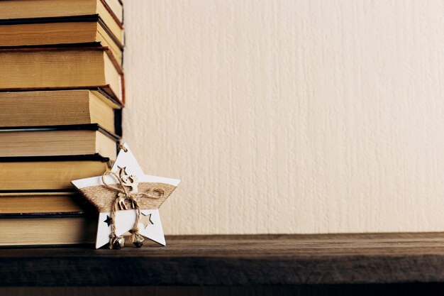 Boeken en een kerstboom met kegels en een sterdecoratie op een oude houten plank.