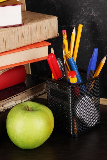 Boeken en magister pet tegen schoolbord op houten tafel close-up