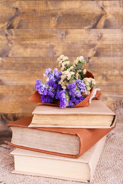 Boeken en wilde bloemen op servet op houten tafel op houten muur achtergrond