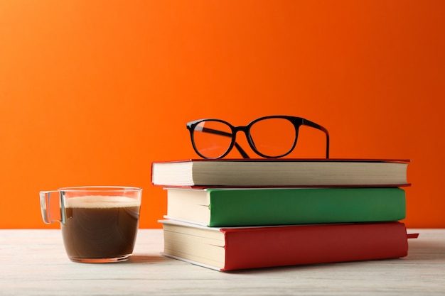 Boeken, kopje koffie en glazen op houten tafel, ruimte voor tekst