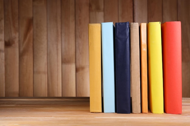 Boeken op houten tafel op houten muur achtergrond