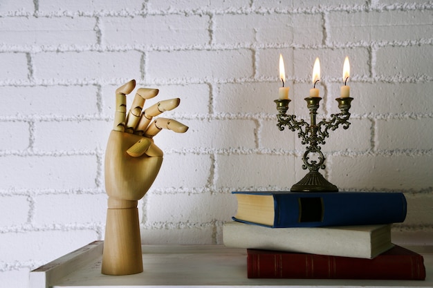 Boekenplank met boeken en kandelaar op bakstenen muur