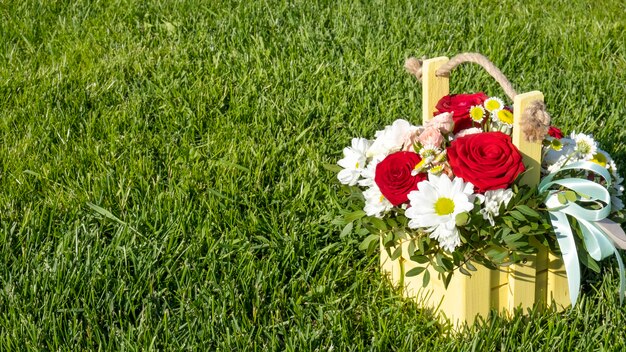 Boeket bloemen in een houten kist op een groen gras. Ruimte kopiëren