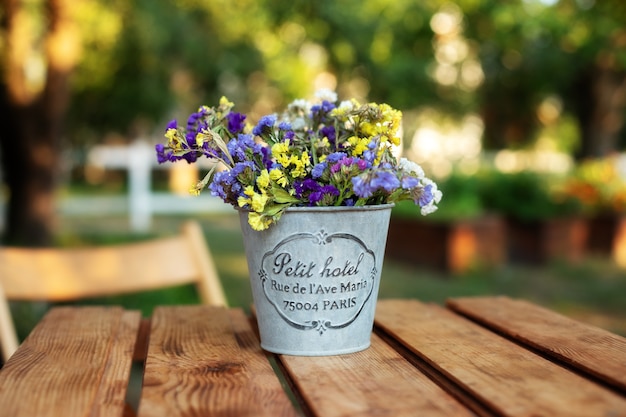 Boeket bloemen in vintage vaas op houten tafel in de tuin. gezellige inrichting van patiotuin