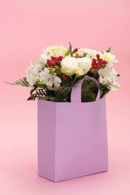 Boeket bloemen in violette papieren zak op roze achtergrond