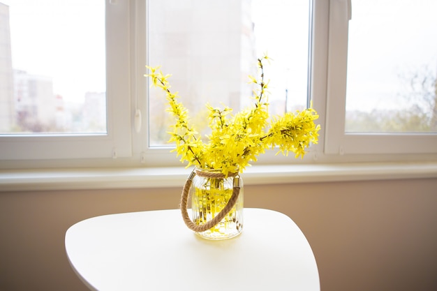 Boeket gele bloemen in een vaas op een witte tafel