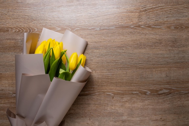 Boeket gele tulpen op een houten lichte achtergrond.