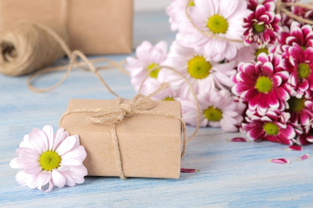 Boeket herfstbloemen van roze chrysanten en geschenkdozen op een blauwe houten tafel