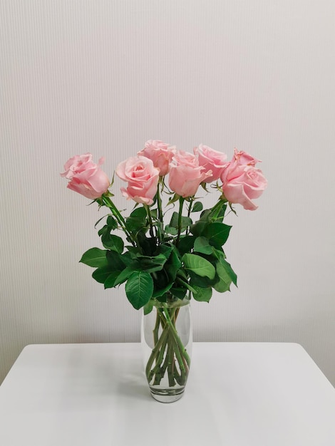 Boeket in een vaas met roze rozen op een tafel in een minimalistische witte keuken