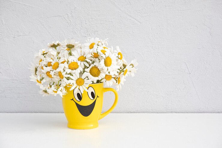 Boeket kamille bloemen in grappige gele beker op tafel Kopieer ruimte vooraanzicht