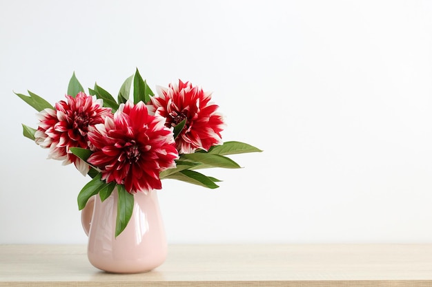 Boeket rode dahlia's in een kruik op tafel