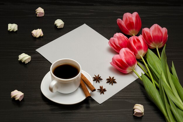 Boeket roze tulpen, een kopje koffie, marshmallow en een vel papier