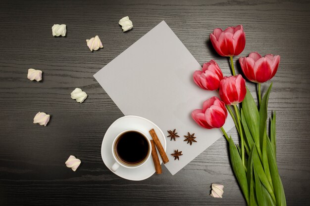 Boeket roze tulpen, een kopje koffie, marshmallow en een vel papier