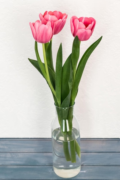 boeket roze tulpen in een glazen vaas op een witte achtergrond