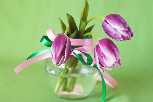 Boeket roze tulpen in een transparante vaas op een groene achtergrond