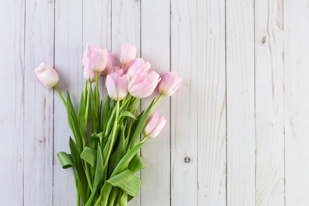 Boeket roze tulpen op een houten ondergrond.