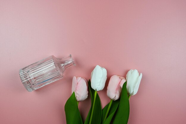 Boeket tulpen en glazen vaas op een roze achtergrond