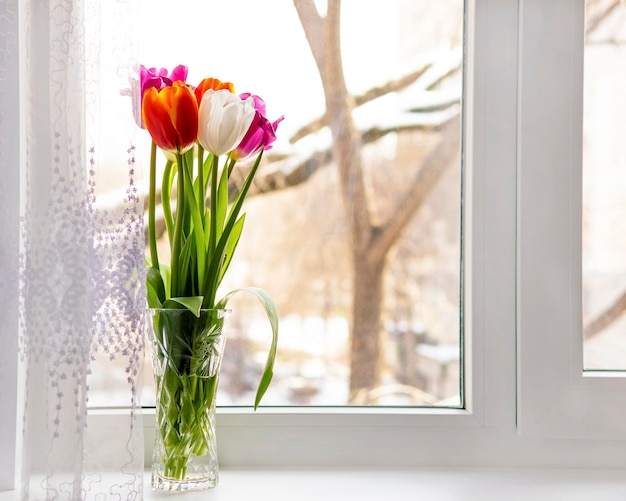 Boeket tulpen in een vaas op het raam Concept moederdag pasen lente liefde