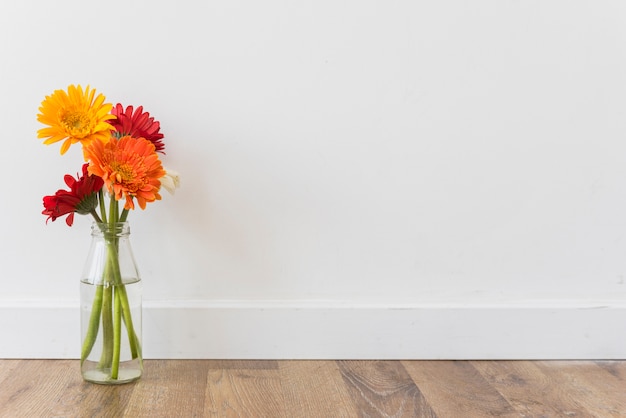 Boeket van bloemen in vaas dichtbij muur