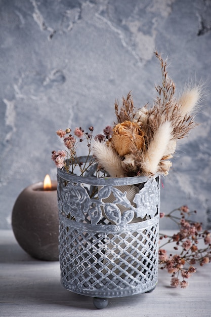 Boeket van droge bloemen in tinnen vaas op witte houten tafel