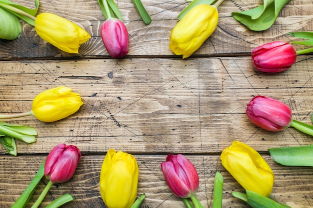 Boeket van gele en roze tulpen op een houten achtergrond.