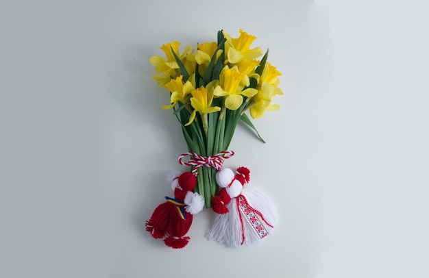 Boeket van gele narcissen gebonden met rood-witte martenitsa, martisor op witte achtergrond kopie ruimte