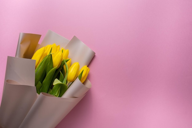 Boeket van gele tulpen op een roze achtergrond.