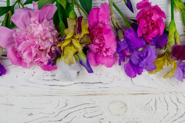 Boeket van kleurrijke iris bloemen en roze pioenrozen op een witte houten achtergrond Bovenaanzicht kopie ruimte