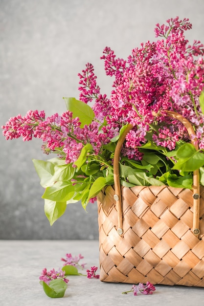 Boeket van kleurrijke lila bloemen in een rieten mand op betonnen ondergrond